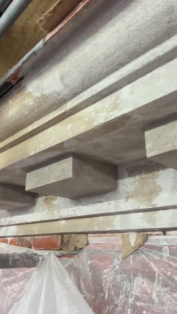 Putsat listverk med konsoler under takfoten på en fasad under renovering