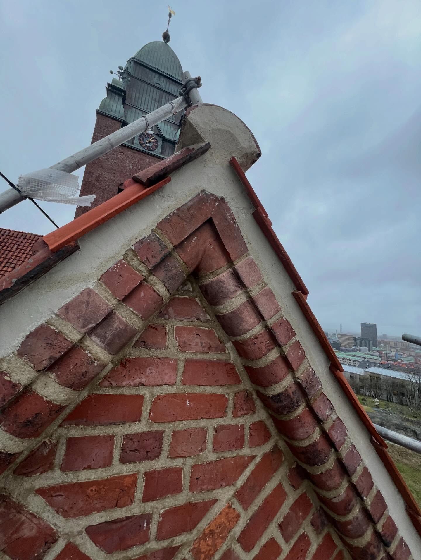 Tegelgavel med takpannor på Masthuggskyrkan, med kyrktornet och Göteborg i bakgrunden
